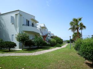 a white building with trees and a grass yard at Mousses Apartments & Studios in Kissamos