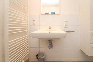 a white bathroom with a sink and a mirror at Rote-Muehle in Greetsiel +5 photos