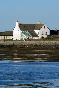 a large white building next to a body of water at No 1 Broughton Bed & Breakfast in Pierowall