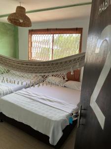 um par de camas num quarto com uma rede de descanso em Alojamiento BAMBUU em Ríohacha