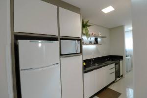 a kitchen with white cabinets and a white refrigerator at Apartamento Familiar III Próximo Beto Carrero e Praia in Penha