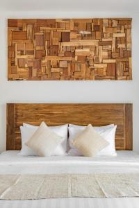 a bed with a wooden headboard and two pillows at Baliterraneo Boutique Resort in Seminyak