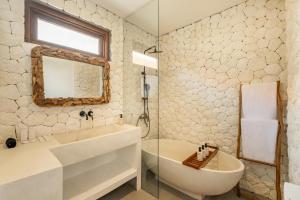 a bathroom with a sink and a tub and a mirror at Baliterraneo Boutique Resort in Seminyak