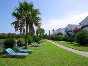 a row of chaise lounges in a park with palm trees at Mousses Apartments & Studios in Kissamos