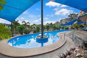 a swimming pool at a resort with blue skies at Sunset Penthouse - Unique Panoramic Rooftop Retreat in Larrakeyah
