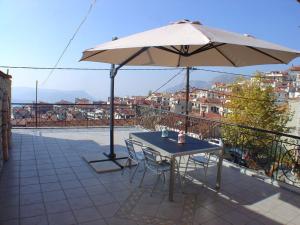 Ariadne Guesthouse في أراخوفا: طاولة مع مظلة فوق شرفة