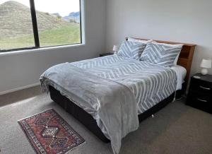 a bedroom with a bed with a window and a rug at Share our rural Havelock North home - With stunning views in Havelock North