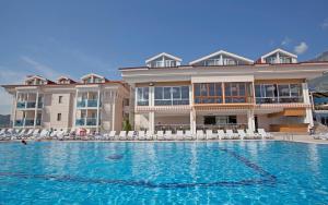 a large building with a large swimming pool with chairs at Aes Club Hotel in Oludeniz