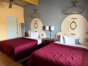two beds in a hotel room with red sheets at Cinderella Motel in Hollister
