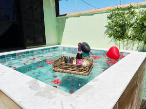 Casa aconchegante a 7 min da Praia في بوزيوس: زجاجة نبيذ في سلة في حمام سباحة