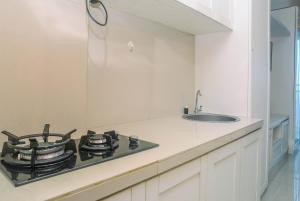 a kitchen with a stove and a sink at Minimalist and Comfy Studio at Grand Dhika City Apartment By Travelio in Bekasi