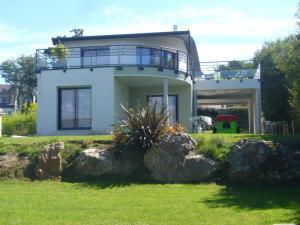 a white house with a balcony and some rocks at kermajo in Plougastel-Daoulas
