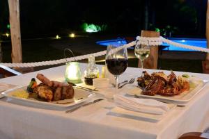 a table with two plates of food and a glass of wine at Kisiwa on the Beach in Paje