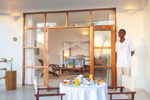 a man standing in a room with a table at Kisiwa on the Beach in Paje
