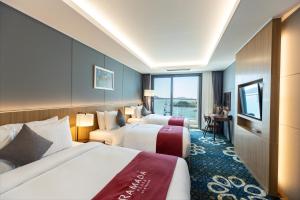 a hotel room with two beds and a window at Ramada Plaza by Wyndham Dolsan Yeosu in Yeosu