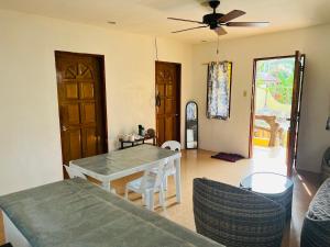 a living room with a table and chairs and a ceiling fan at GJES HOSTEL and GUESTHOUSE in Moalboal