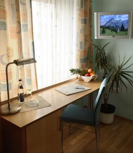 einen Schreibtisch mit einer Lampe und einem Stuhl in einem Zimmer in der Unterkunft Goldener Adler in Sulzheim