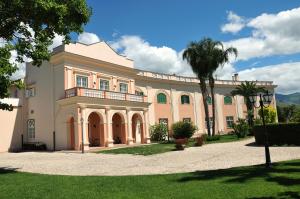 a large house with a palm tree in front of it at Villa Irlanda Grand Hotel in Gaeta
