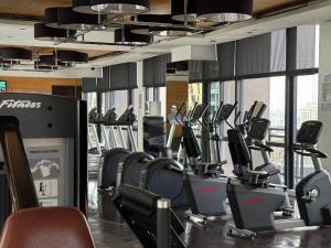 un gimnasio con filas de cintas de correr y máquinas elípticas en Condo in Makati with Fast WiFi, Free Pool, Netflix and Own Balcony, en Manila