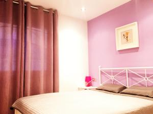 リョレート・デ・マルにあるLloret Beach Apartmentsの紫の壁のベッドルーム1室、ベッド1台が備わります。