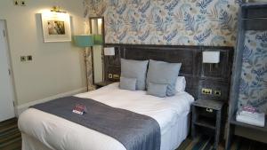a bedroom with a large bed with a wooden headboard at The Hippodrome Wetherspoon in March
