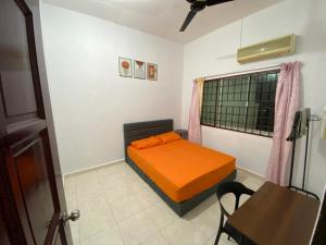 a small bedroom with an orange bed and a table at Pagoh Town homestay 2 in Pagoh