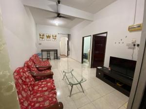 a living room with a red couch and a television at Pagoh Town homestay 2 in Pagoh
