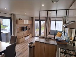 a kitchen and living room of a caravan at Ferienhaus Chalet Spaciosa Lauwersmeer in Lauwersoog +8 photos