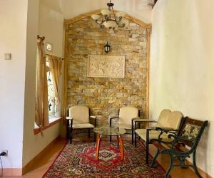 a room with chairs and a table and a brick wall at Villa Sevilla 3 Bedrooms BPPK Ciloto Puncak by Damaresa in Tjiandjur