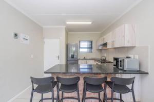 eine Küche mit einer Theke mit vier Stühlen darin in der Unterkunft Cozy Apartment in Brackenfell, Cape Town, ZA in Brackenfell