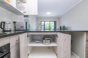 eine Küche mit weißen Schränken und einem Topf auf einem Regal in der Unterkunft Cozy Apartment in Brackenfell, Cape Town, ZA in Brackenfell + 22 Fotos