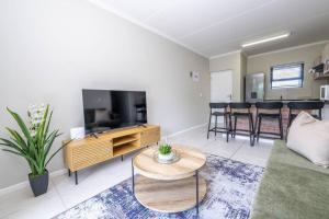 ein Wohnzimmer mit einer Couch, einem Fernseher und einem Tisch in der Unterkunft Cozy Apartment in Brackenfell, Cape Town, ZA in Brackenfell