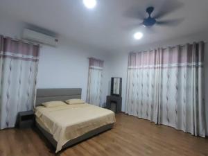 a bedroom with a bed and a ceiling fan at Homezstay Swallow Airport Miri in Miri