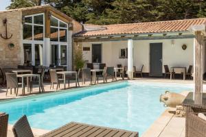 a pool with chairs and tables and a house at Hôtel Restaurant & Spa Plaisir in Le Bois-Plage-en-Ré
