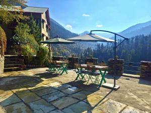 two tables and chairs with umbrellas on a patio at Jalori House in Jibhi