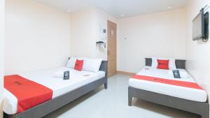 una camera da letto con due letti e una TV a parete di RedDoorz at Isabelita Hotel Tuguegarao City a Tuguegarao