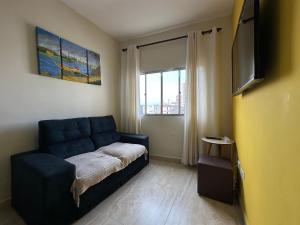a living room with a blue couch and a window at Apto com Sacada e Wi-Fi – 5 min da Praia! in Samaritá