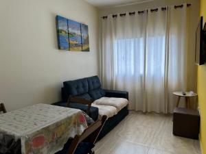 a living room with a blue couch and a table at Apto com Sacada e Wi-Fi – 5 min da Praia! in Samaritá