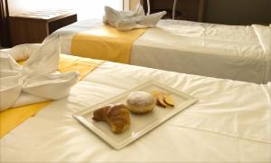 a plate of pastries and croissants on a bed at Hotel La Fenice in Lignano Sabbiadoro