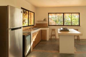 Una cocina con refrigerador de acero inoxidable y una mesa. en La Sana Surf Hotel, New design, Few mn drive to the beach, en Santa Teresa Beach