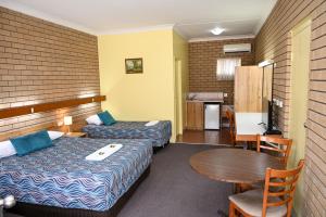 a hotel room with two beds and a table at Holbrook Town Centre Motor Inn in Holbrook