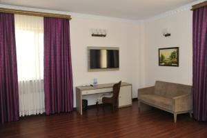 a living room with a couch and a desk and a television at Sunkar Hotel in Atyrau