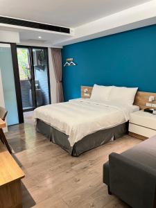 una camera da letto con un letto grande con una parete blu di Greenight Hotel a Taichung