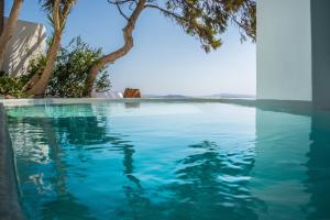 una piscina con agua azul y árboles en Pina Caldera Residence, en Oia