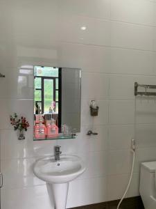 a white bathroom with a sink and a mirror at Duong Riverside Homestay in Phong Nha