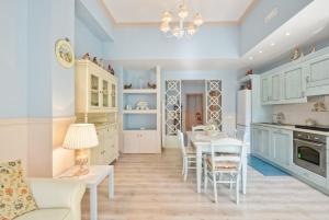 - une cuisine avec des placards blancs, une table et des chaises dans l'établissement La Bouganville Holiday House, à Agropoli