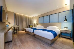 a large hotel room with two beds and a television at Echarm Hotel Guiyang Municipal Government Lin Cheng Xi Road Metro Station in Guiyang