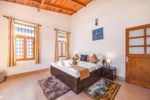 a bedroom with a bed and a wooden door at Alaya Stays 3BHK Rose Haven near Kainchi Dham in Bhowāli