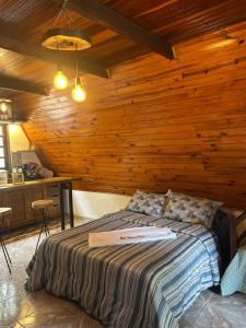 a bedroom with a bed with a wooden wall at Chalé Estância do Coruja in Salesópolis +52 photos