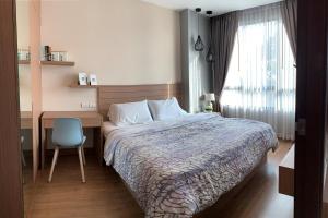 a bedroom with a bed and a desk and a chair at Sky condo by Grace in Chon Buri